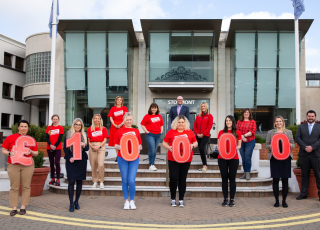 Welcoming guests outside modern hotel entrance with friendly staff, showcasing hospitality and contemporary architecture.