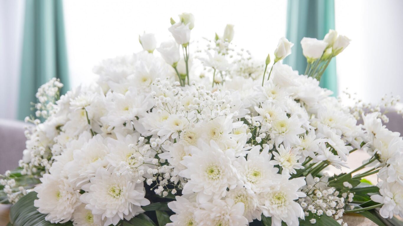 Elegant white flower arrangement with soft green curtains, creating a serene and welcoming hotel atmosphere.
